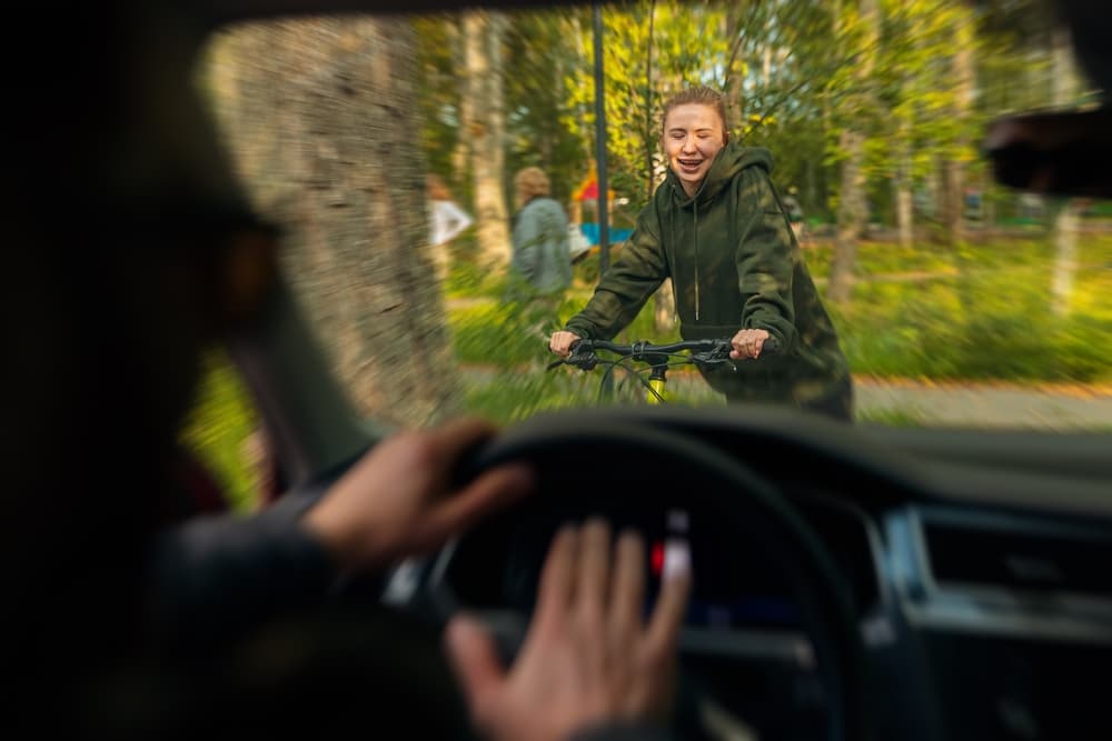 Driver hits female cyclist at high speed, depicting an accident. The concept involves a distracted man on a bicycle using a phone.